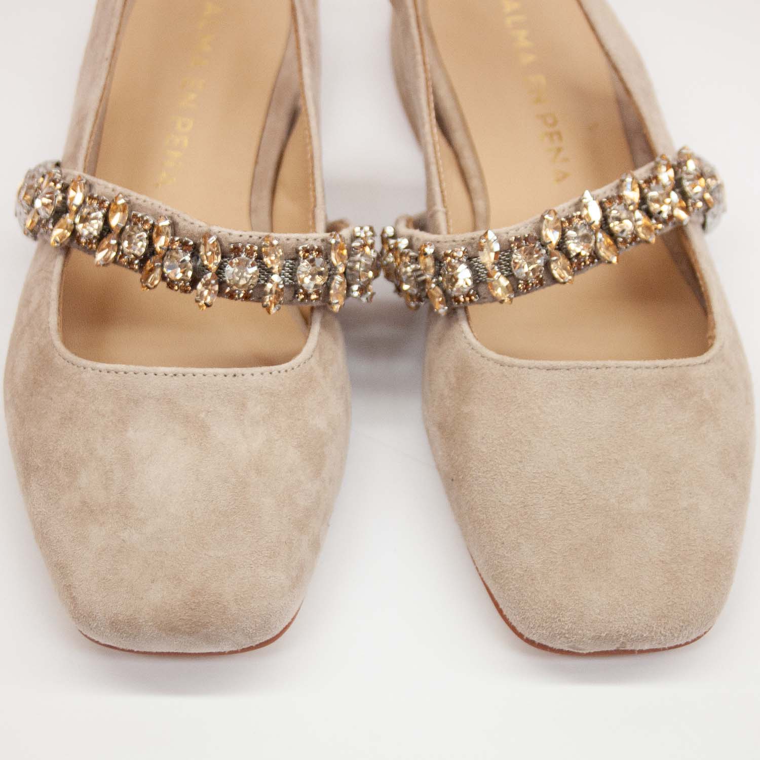Zbliżenie na pasek balerin ozdobiony bogato osadzonymi kryształkami, kontrastującymi z miękkim zamszem.
