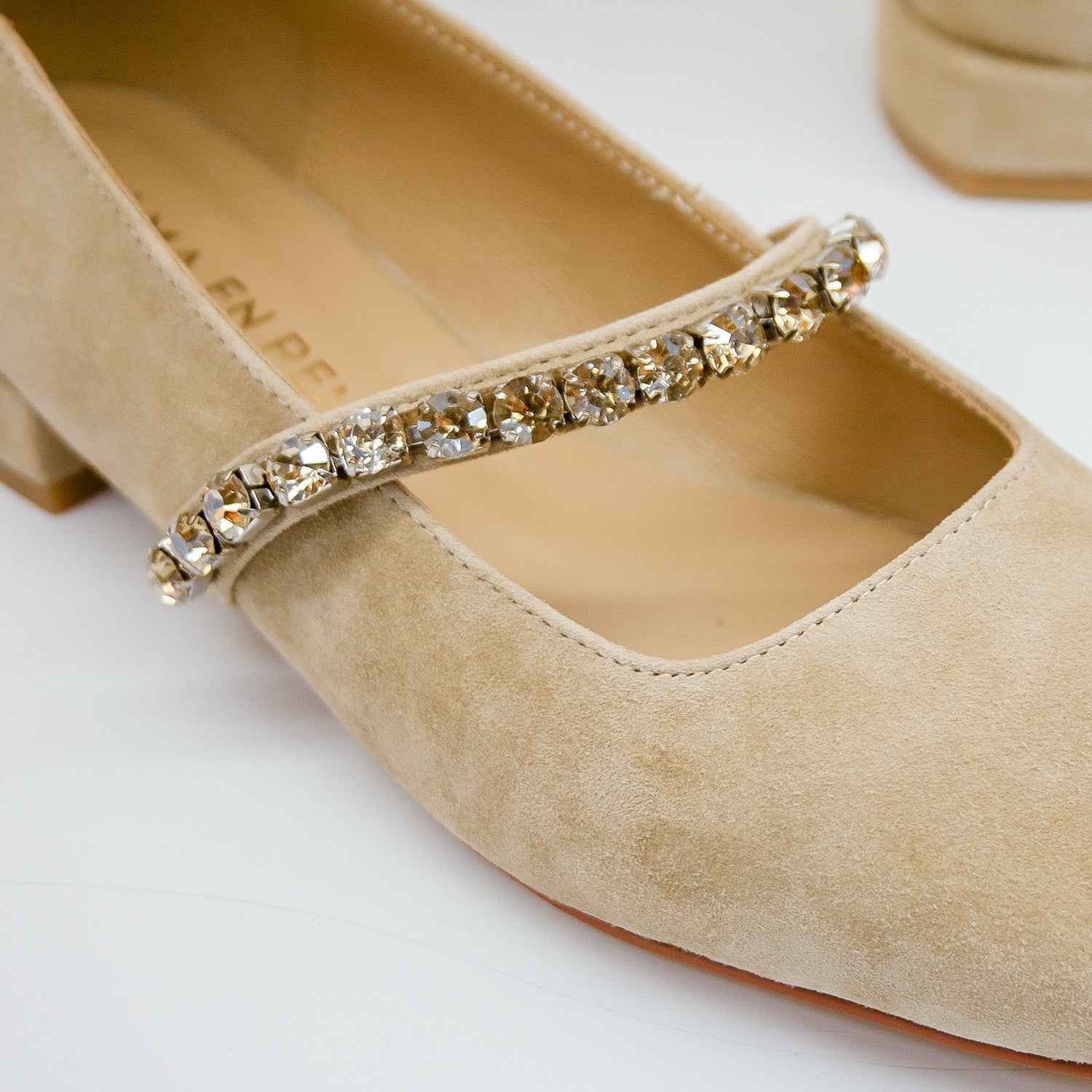 Zbliżenie na kryształkowy pasek balerin Alma En Pena – beżowy zamsz i dekoracja w pełnej ostrości.