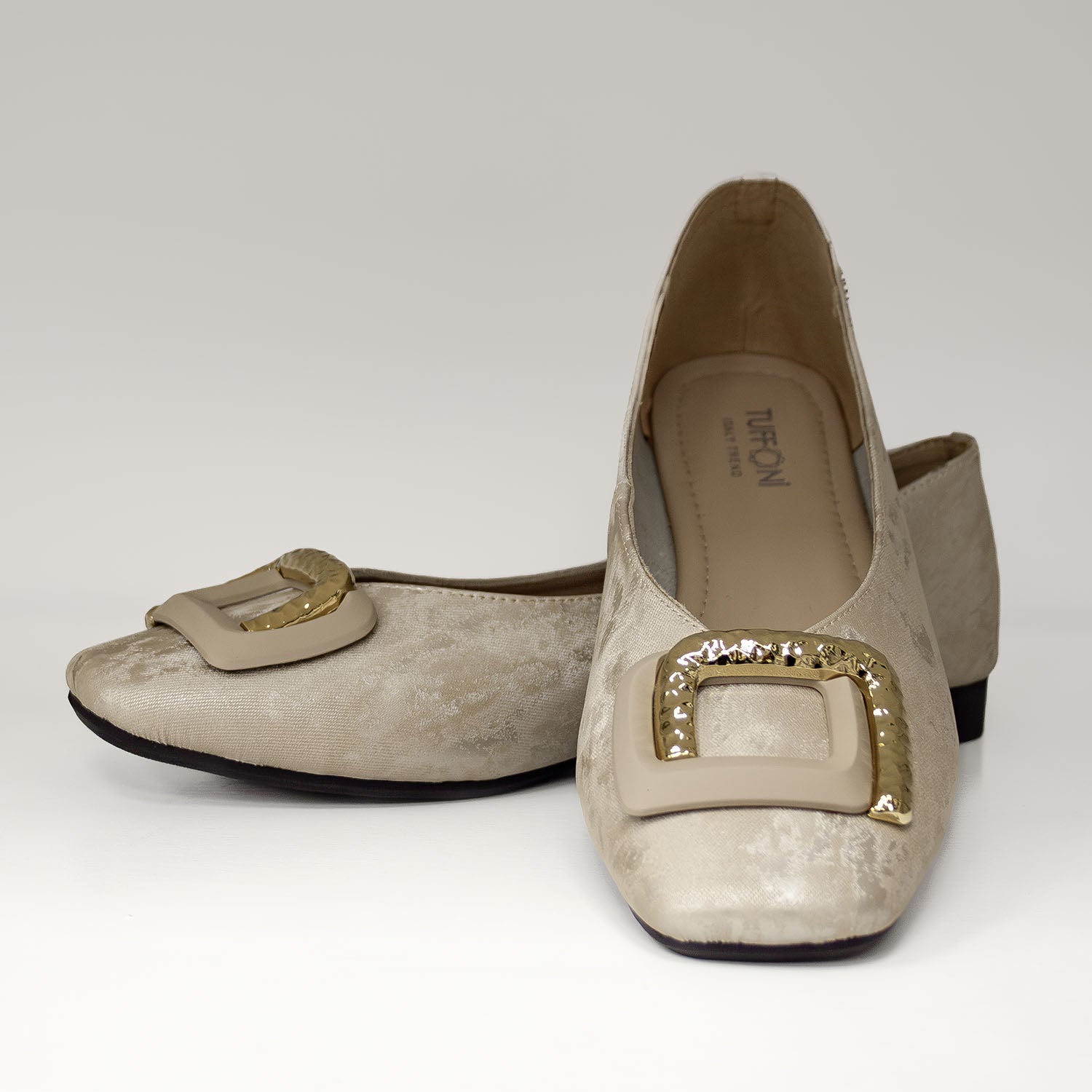 Przód beżowych balerin Tuffoni z aplikacją w geometrycznym kształcie, na tle białym.