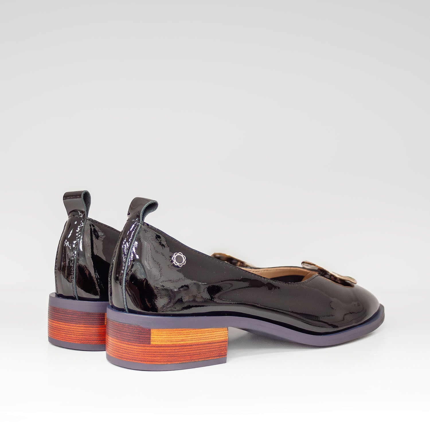 Baleriny Tuffoni – czarne, lakierowane, włoskie, z naturalnej skóry oraz z ozdobą na przodzie cholewki o szmaragdowym odcieniu - widok z tyłu.