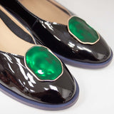 Baleriny Tuffoni – czarne, lakierowane, włoskie, z naturalnej skóry oraz z ozdobą na przodzie cholewki o szmaragdowym odcieniu - zbliżenie na szmaragdowe oczko.