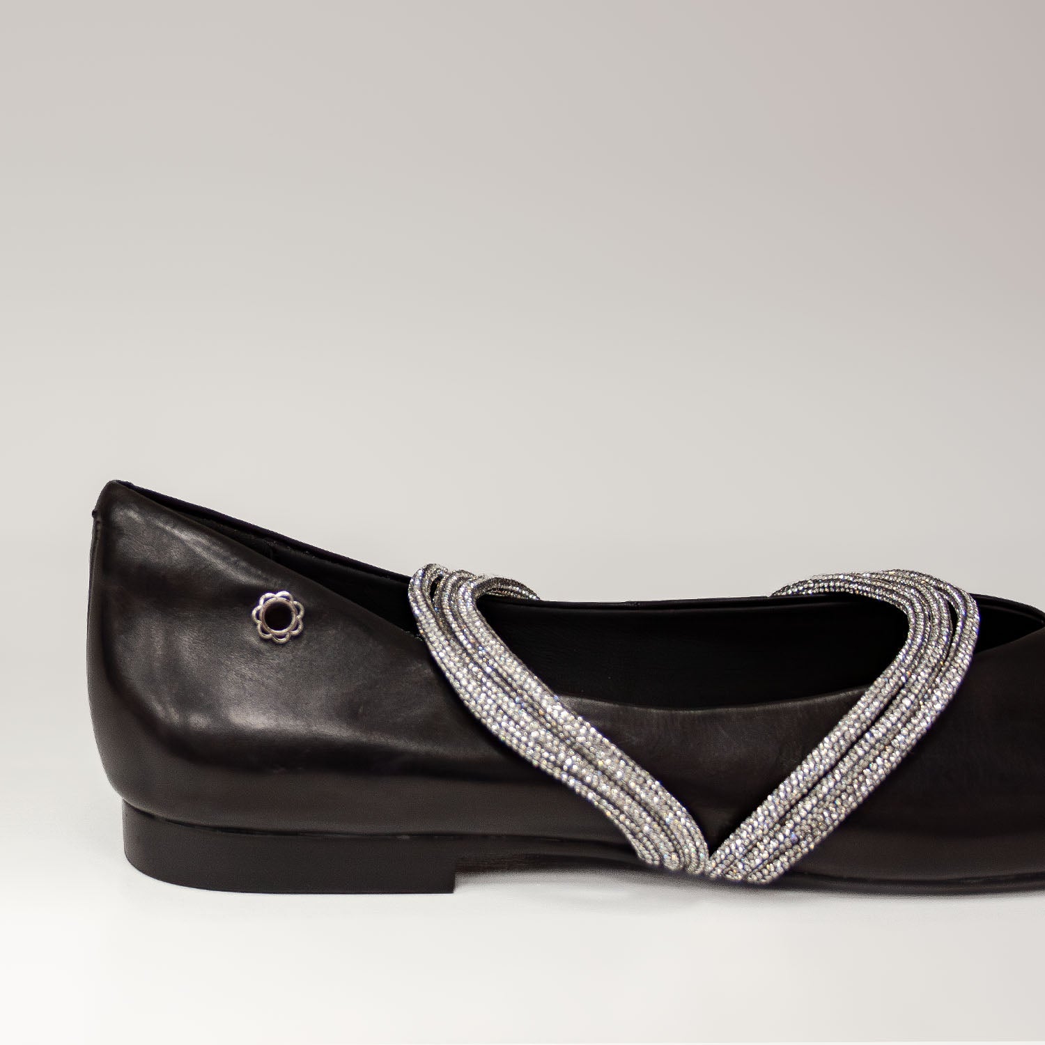 Zbliżenie na ozdobne paski z cyrkoniami w czarnych balerinach Tuffoni – detale biżuteryjnego wykończenia.