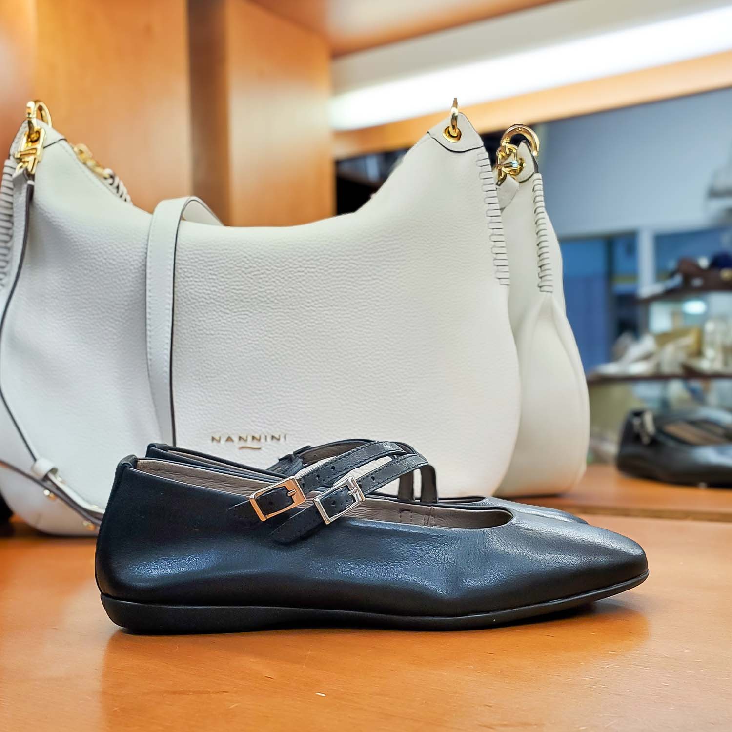 Baleriny Wonders – czarne, skórzane, Mary Jane widok z boku w sklepie Buty i Kawa – balerina ustawiona bokiem na ladzie sklepowej, z widoczną torebką Nannini w tle.