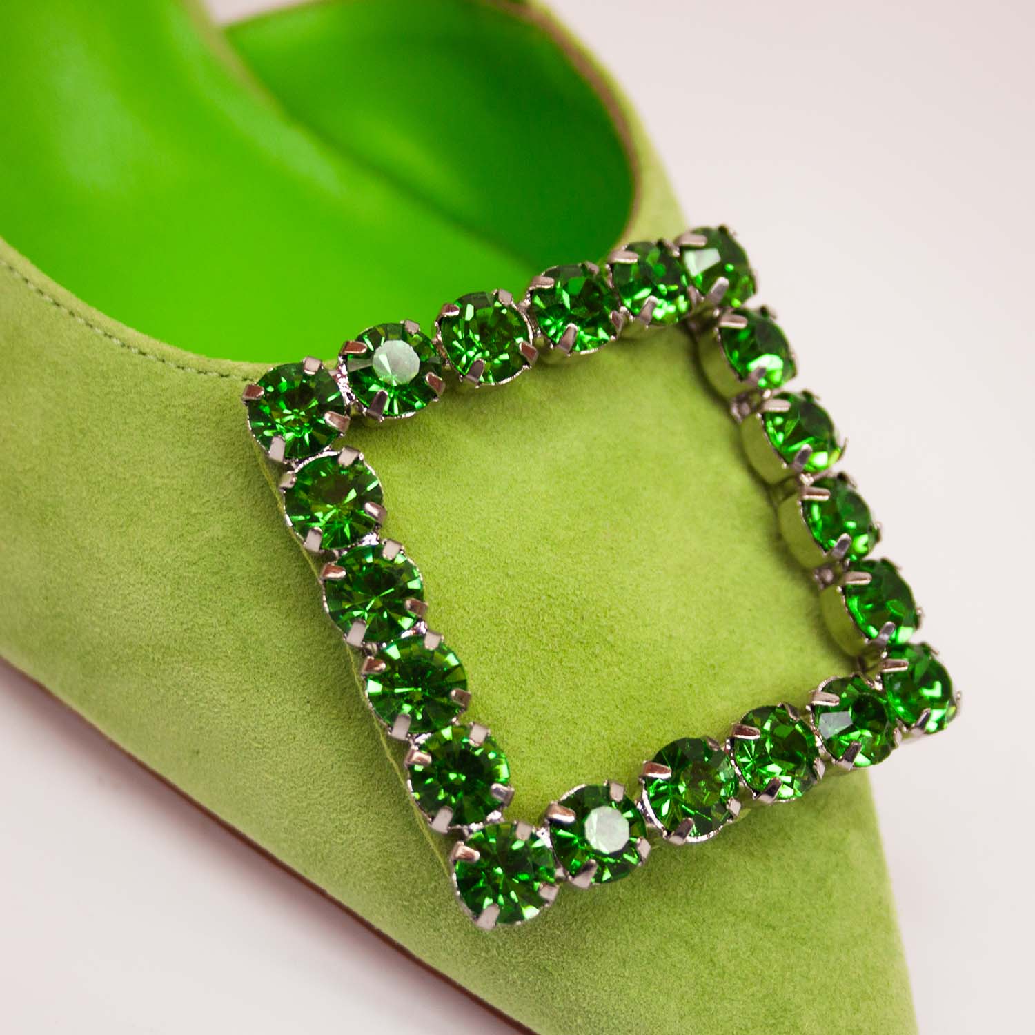 Zbliżenie na cyrkoniową ozdobę czółenek Alma En Pena – detal efektownej klamry z dużych zielonych cyrkonii na nosku zamszowego buta.