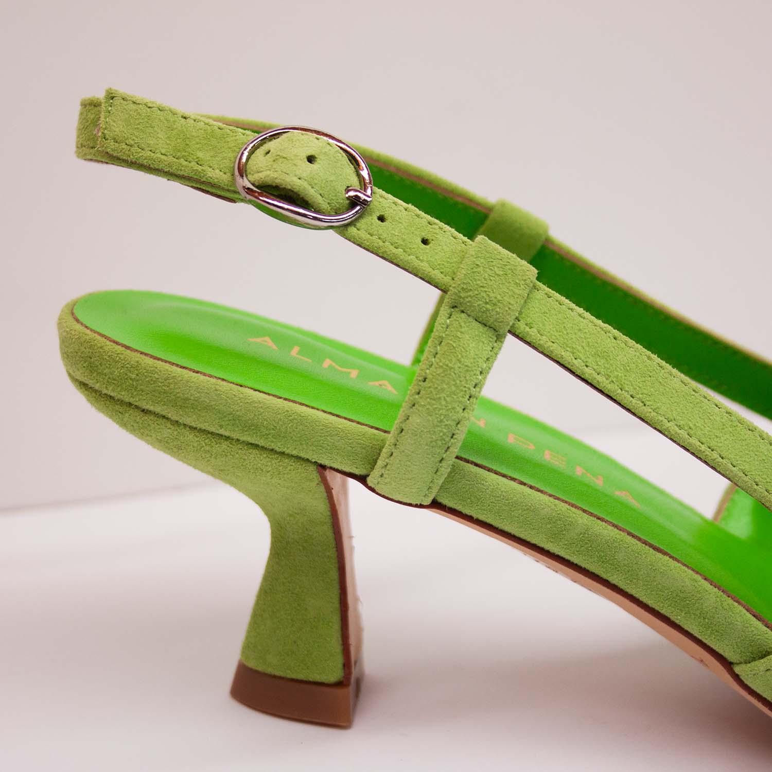 Zbliżenie na sprzączkę paska czółenek Alma En Pena – fragment regulowanego paska i wyściółki w odcieniu limonkowym, ukazany z boku przy obcasie.