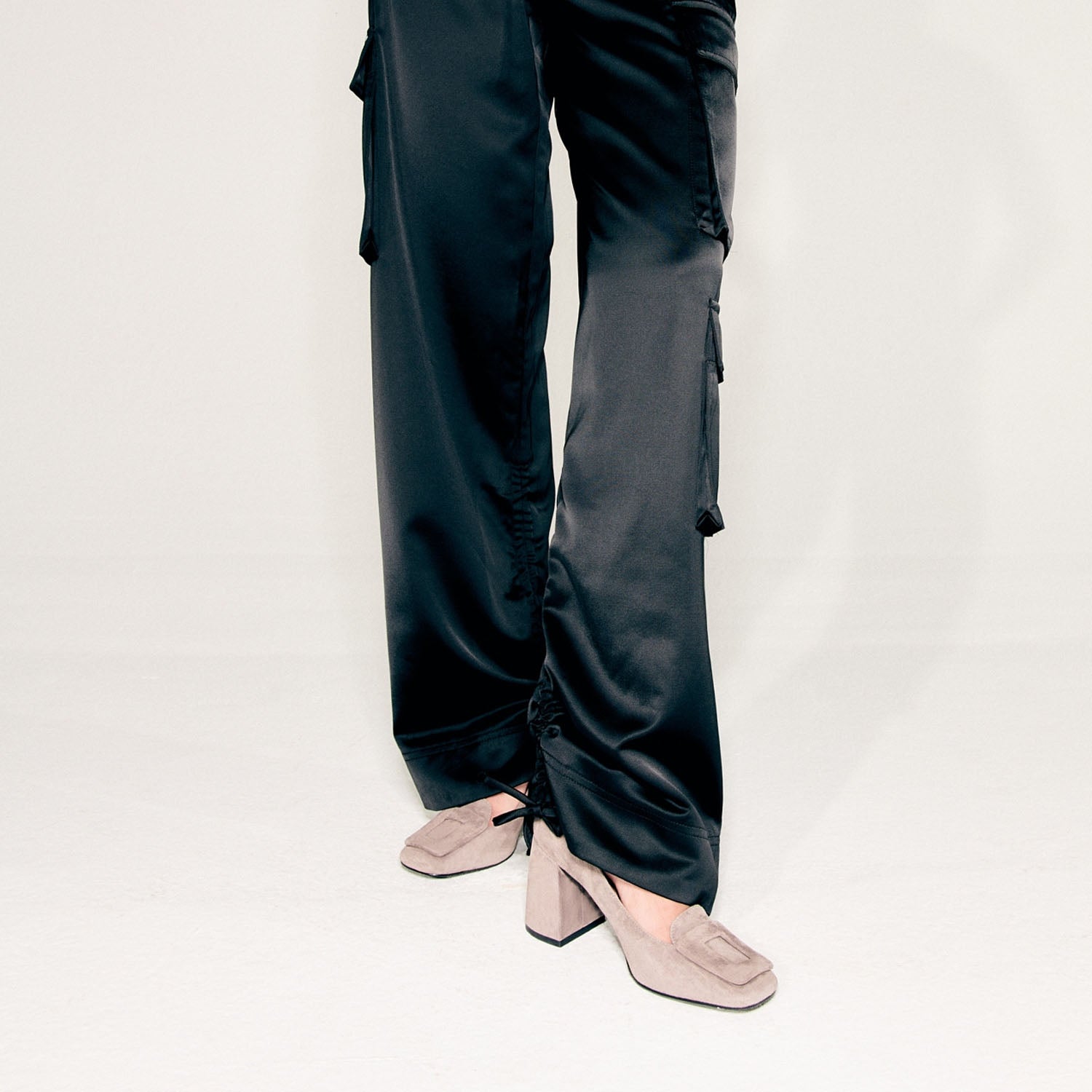 Czółenka Bibi Lou zamszowe, skórzane na słupku – ujęcie na modelce w czarnych satynowych spodniach, eksponujące wysokość obcasa i proporcje buta