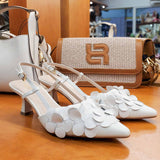 Czółenka Tosca Blu – kremowe, skórzane, włoskie – ustawione na tle torebek w butikowym wnętrzu, z widocznymi detalami i obcasem typu kaczuszka.