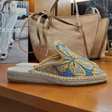 Espadryle Macarena na wystawie sklepu obok plecionych torebek – naturalny look z espadrylami na tle lnianych akcesoriów i ekspozycji z katalogiem marki.