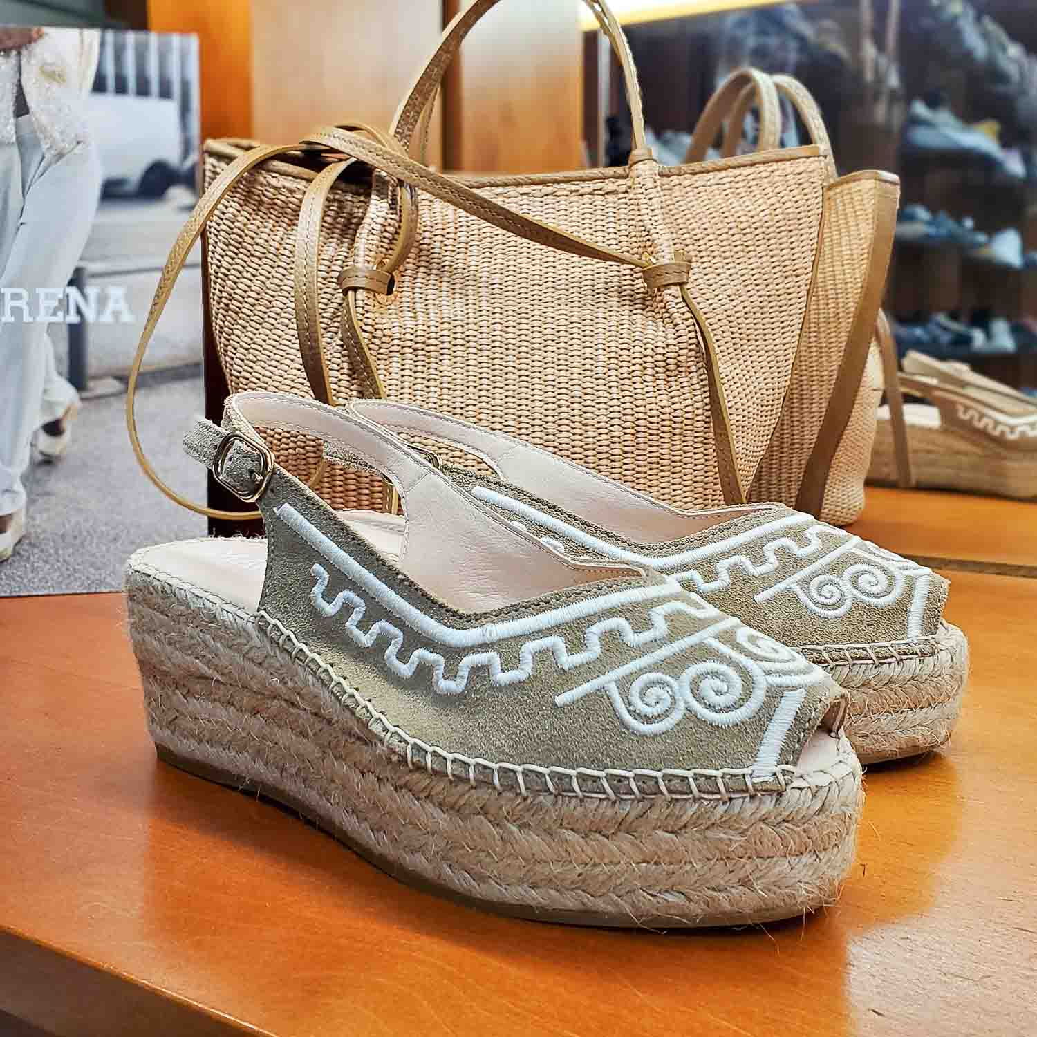 Espadryle Macarena na koturnie na wystawie sklepu obok plecionych torebek – letni klimat z espadrylami i dodatkami w naturalnych odcieniach beżu i słomy.