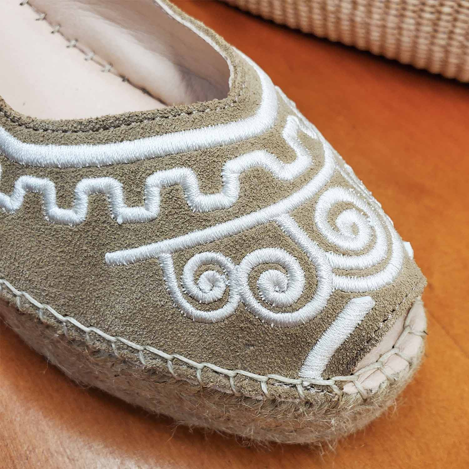 Zbliżenie na haft espadryli Macarena na koturnie – detal białego haftu na beżowej cholewce z miękkiego materiału, z wyraźnym obszyciem i widocznym noskiem.