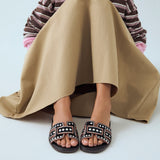 Klapki Bibi Lou – czarne, skórzane, z nitami, stylizacja na modelce – modny letni look z długą spódnicą, klapki jako kobiecy akcent.