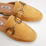 Musztardowe klapki hiszpańskiej marki Bibi Lou typu mule wykonane z miękkiego, naturalnego zamszu - zbliżenie eksponujące złotą ozdobną klamrę.