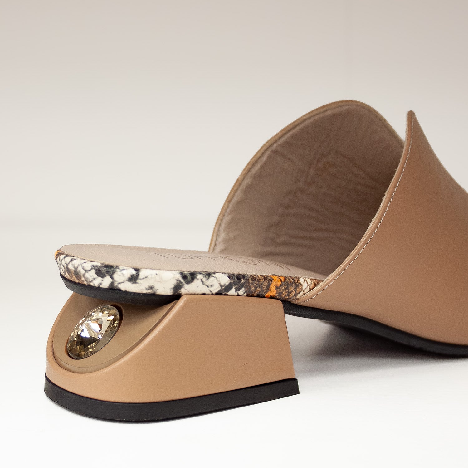 Zbliżenie na obcas klapek Tuffoni z kryształem i kontrastującą wkładką w stylu animal print.