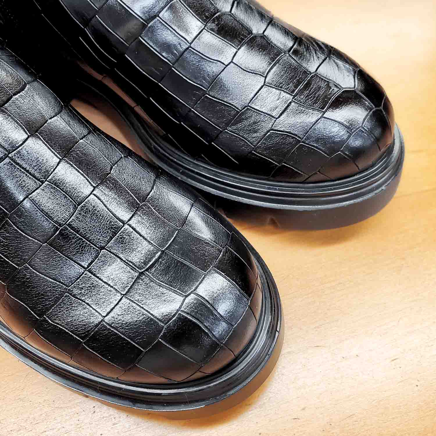 Czarne kozaki BONES od hiszpańskiej marki Wonders z naturalnej skóry licowej o wysokim połysku, tłoczonej w wyrazisty, zwierzęcy wzór na płaskiej podeszwie - zbliżenie na fakturę skóry.