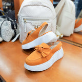 Mokasyny Wonders – pomarańczowe, zamszowe, bez pięty, na platformie – widok z góry w butiku, na tle jasnego plecaka