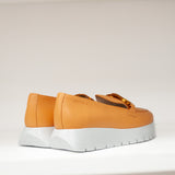 Mokasyny Wonders – pomarańczowe, skórzane, na platformie od strony pięty, z wyraźnie widoczną linią zszycia i lekko zaokrąglonym tyłem cholewki.