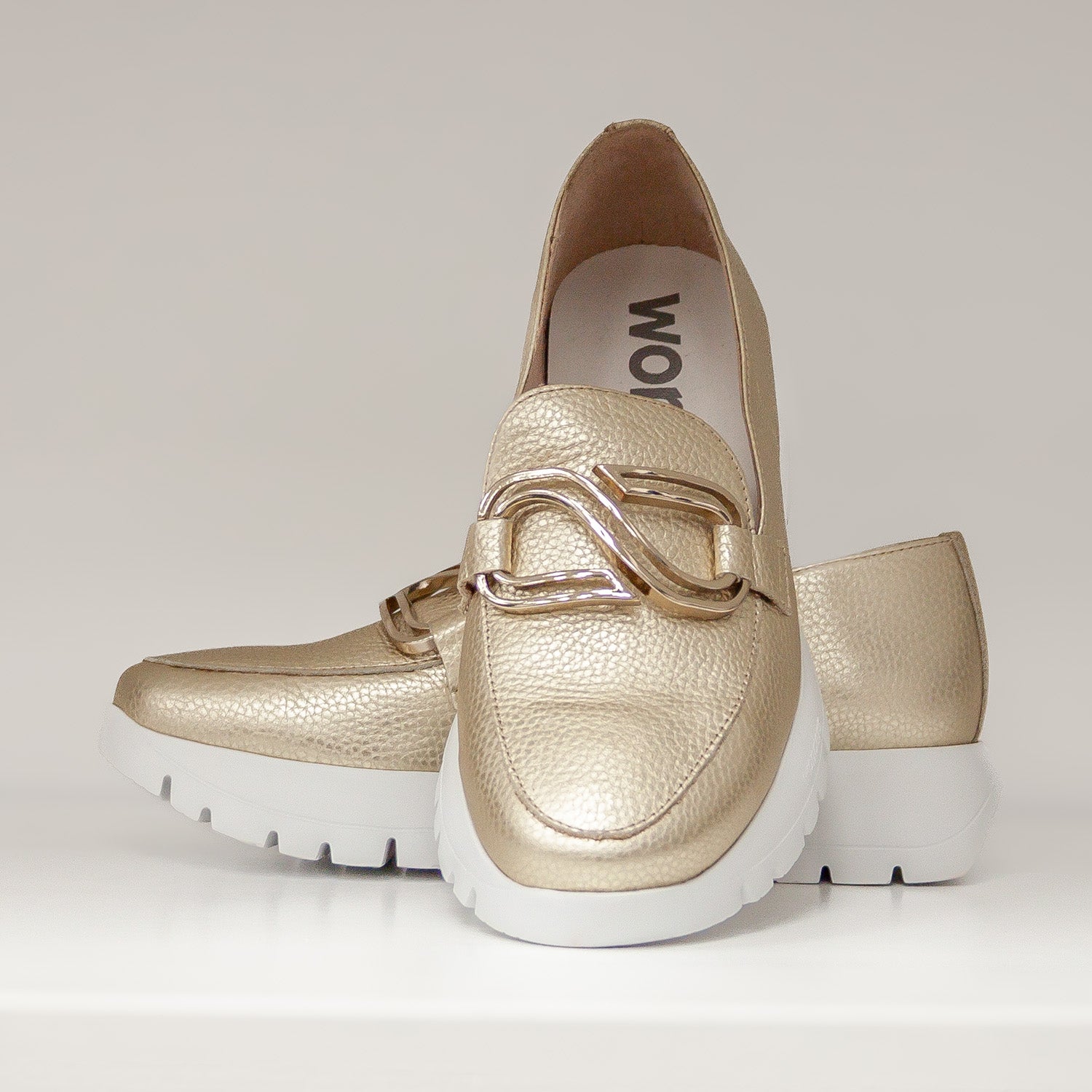 Złote skórzane mokasyny Wonders ustawione jeden na drugim, ozdoba w złotym odcieniu, widok z przodu.