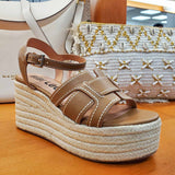 Sandały Bibi Lou brązowe skórzane na koturnie widok pod kątem – stylowe sandały z kontrastowym obszyciem, ustawione przy torebkach w letniej aranżacji.