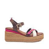 Sandały Igi&Co na koturnie widok z boku – brązowe sandały z paskami w odcieniach fuksji, bieli i ciemnego brązu, osadzone na lekkim koturnie w kolorze naturalnego drewna, widoczne z lewej strony.