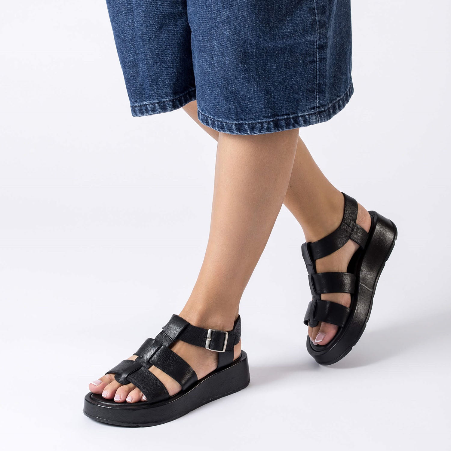 Sandały Wonders, czarne, skórzane, hiszpańskie na platformie – modelka prezentuje sandały na stopach, widoczna wysokość podeszwy i dopasowanie pasków.