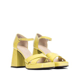 Żółte sandały Wonders z lakierowanej skóry, z wysokim słupkiem i paskiem wokół kostki, widoczne z przodu i boku.