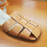 Zbliżenie na pleciony przód pomarańczowych sandałów na niskim obcasie Wonders z zakrytymi palcami i lakierowanym wykończeniem.