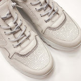 Zbliżenie na białe sneakersy Wonders z perforowaną fakturą i srebrnymi sznurówkami, ujęcie z góry pokazujące detaliczne wykończenie cholewki.