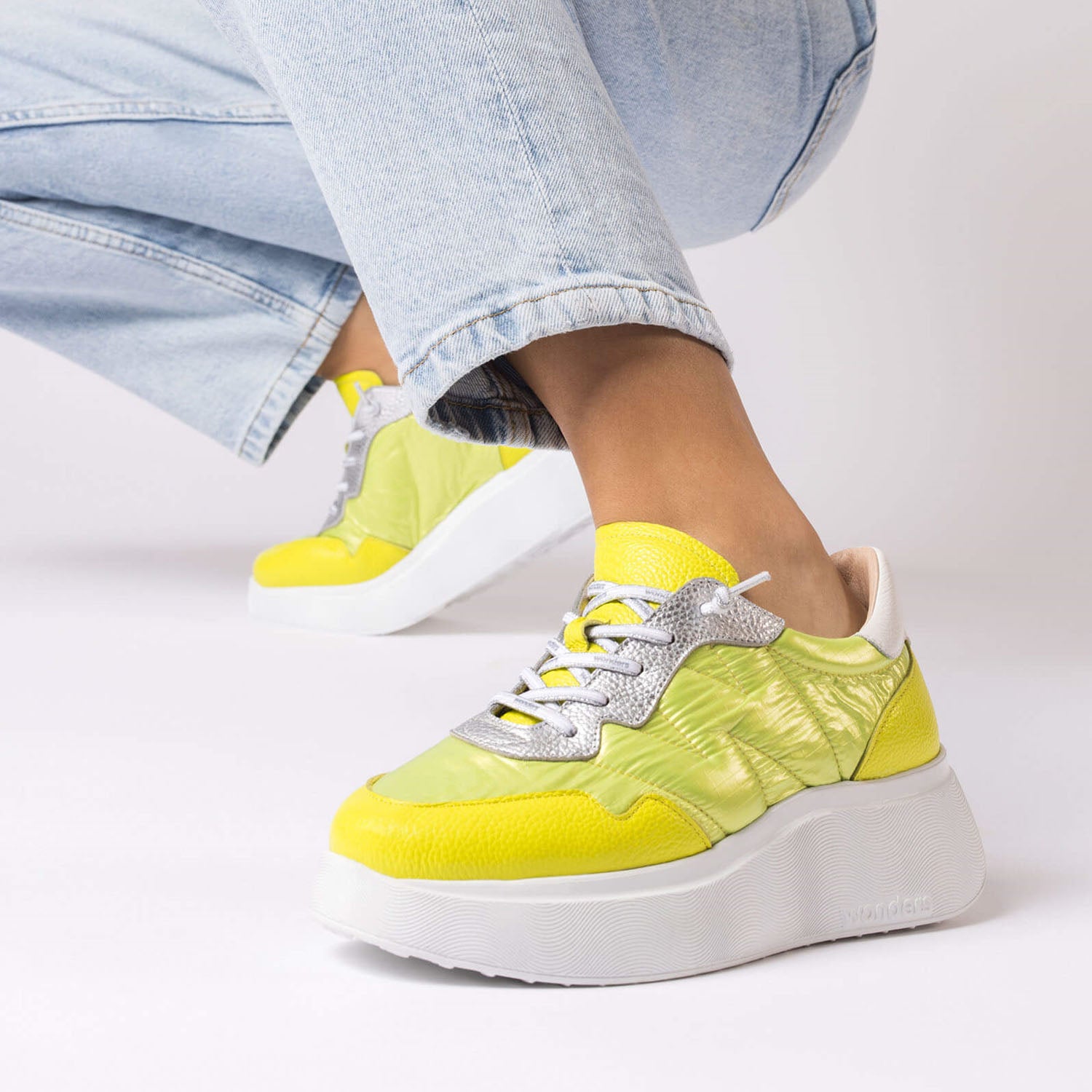 Sneakersy Berlin Wonders – limonkowe, skórzane, na platformie – ujęcie na stopach modelki w jasnych dżinsach