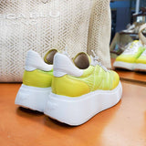Sneakersy Wonders – limonkowe, skórzane, na platformie – widok od tyłu, para ustawiona na drewnianym blacie, w tle torba z plecionki