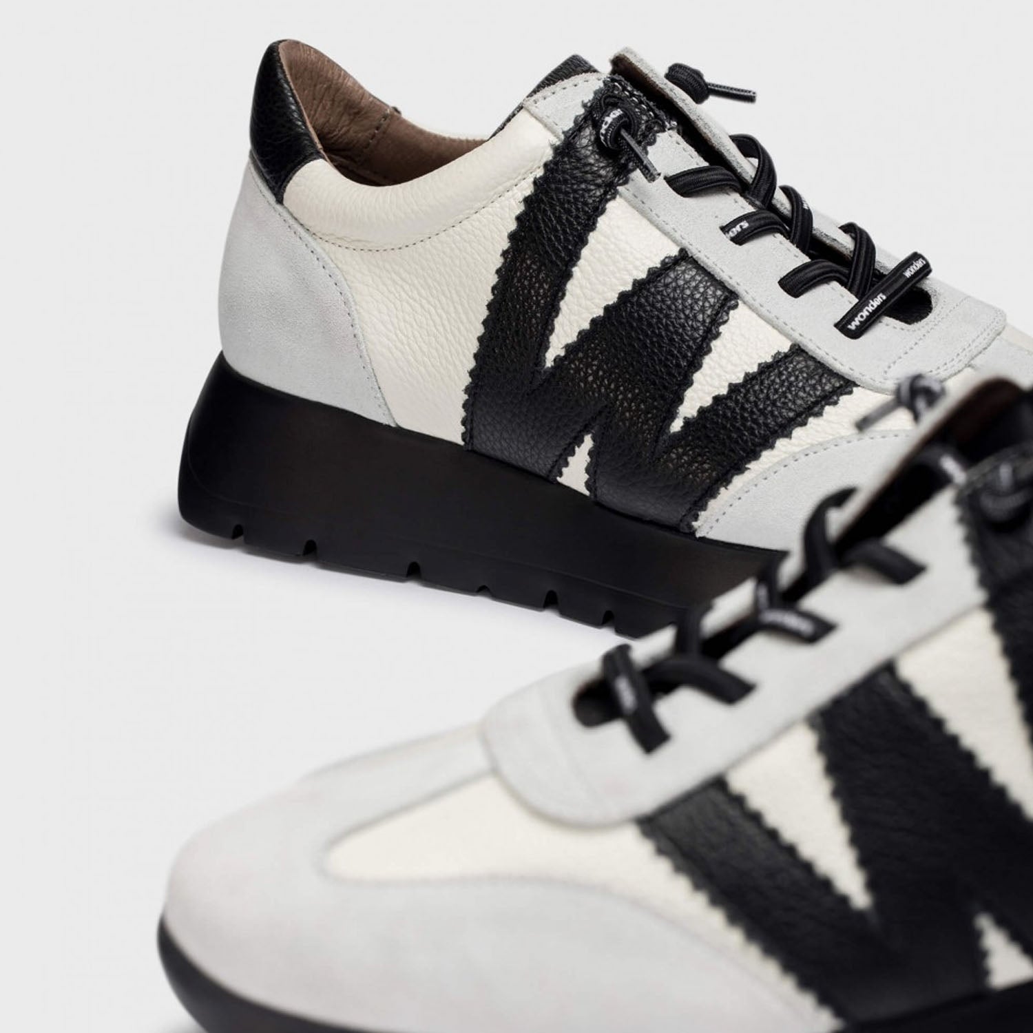 Hiszpańskie sneakersy Wonders – biało-czarne, skórzane, eleganckie z nowe jkolekcji 2025/2026 jesień/zima ze skóry naturalnej licowej i zamszowej, widok pary i zbliżenie na logo.