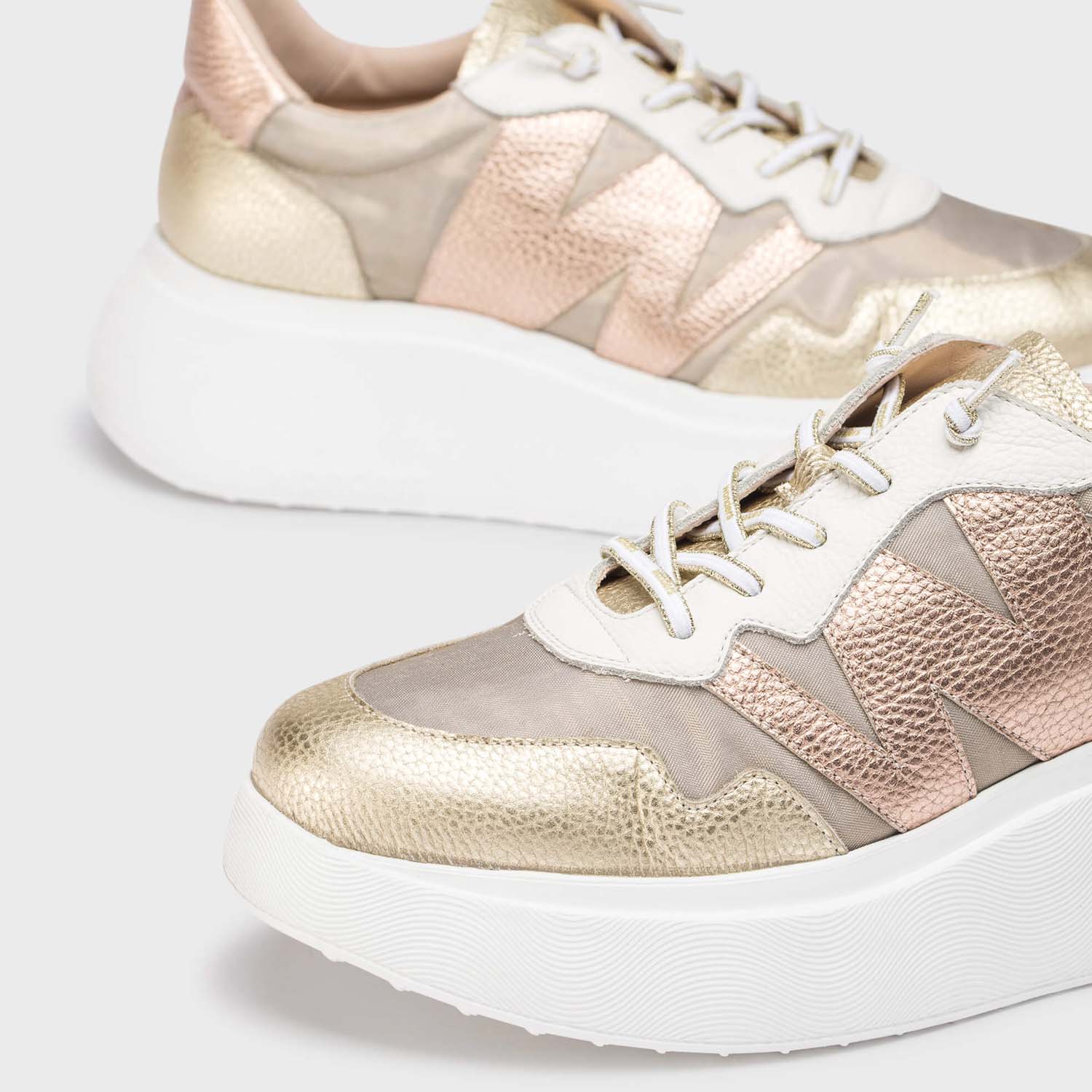 Sneakersy Wonders – złote, skórzane, na platformie w dużym zbliżeniu, z widocznym logo „W” i eleganckim, tłoczonym wzorem skóry.