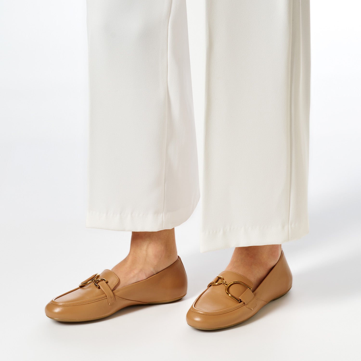 Beżowe mokasyny GEOX Palmaria na nodze, stylizacja z jasnymi spodniami.