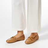 Beżowe mokasyny GEOX Palmaria na nodze, stylizacja z jasnymi spodniami.