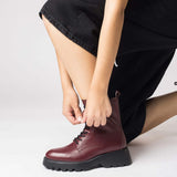 Bordowe botki Wonders w stylizacji – modelka zapina buty na suwak.