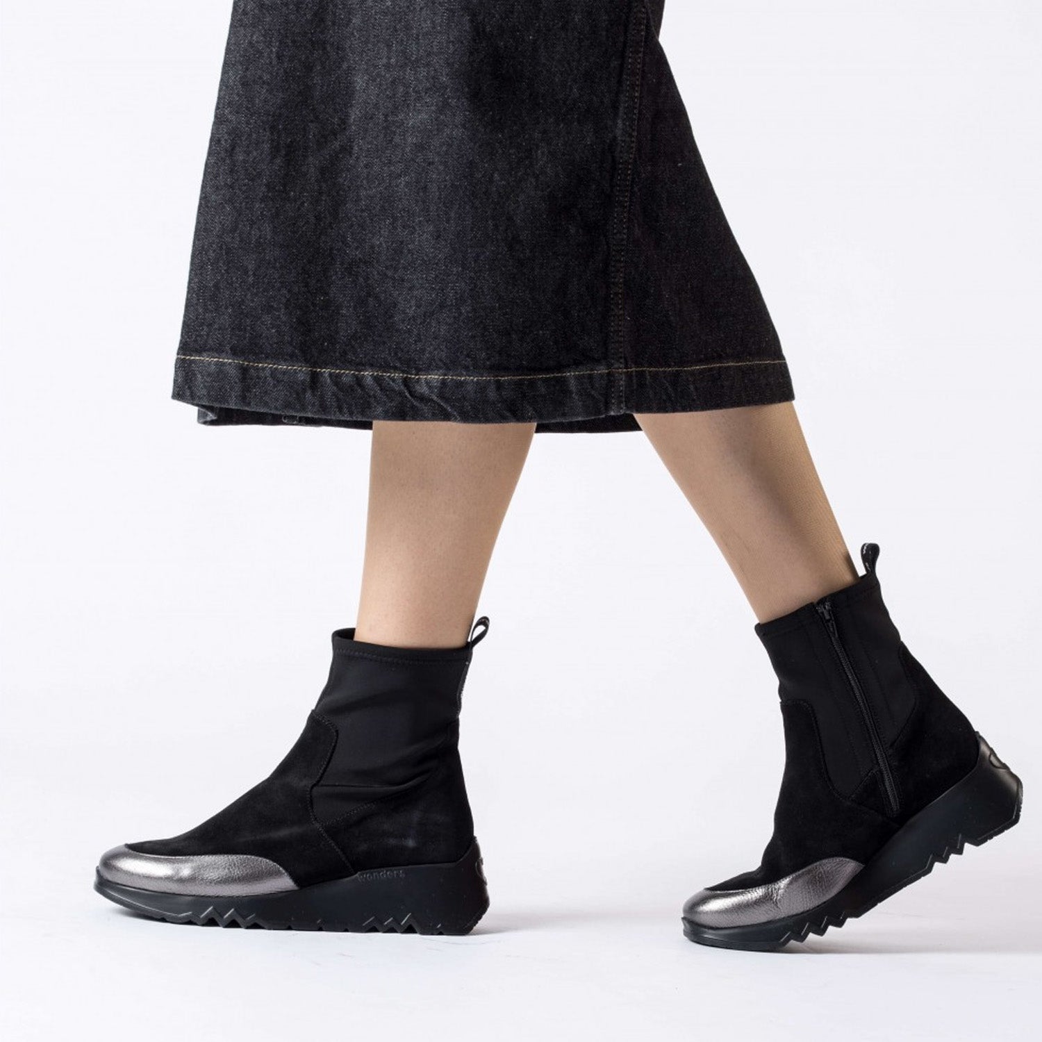 Czarne botki Wonders w stylizacji – modelka nosi je z midi spódnicą.