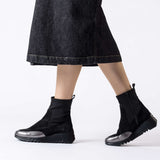 Czarne botki Wonders w stylizacji – modelka nosi je z midi spódnicą.