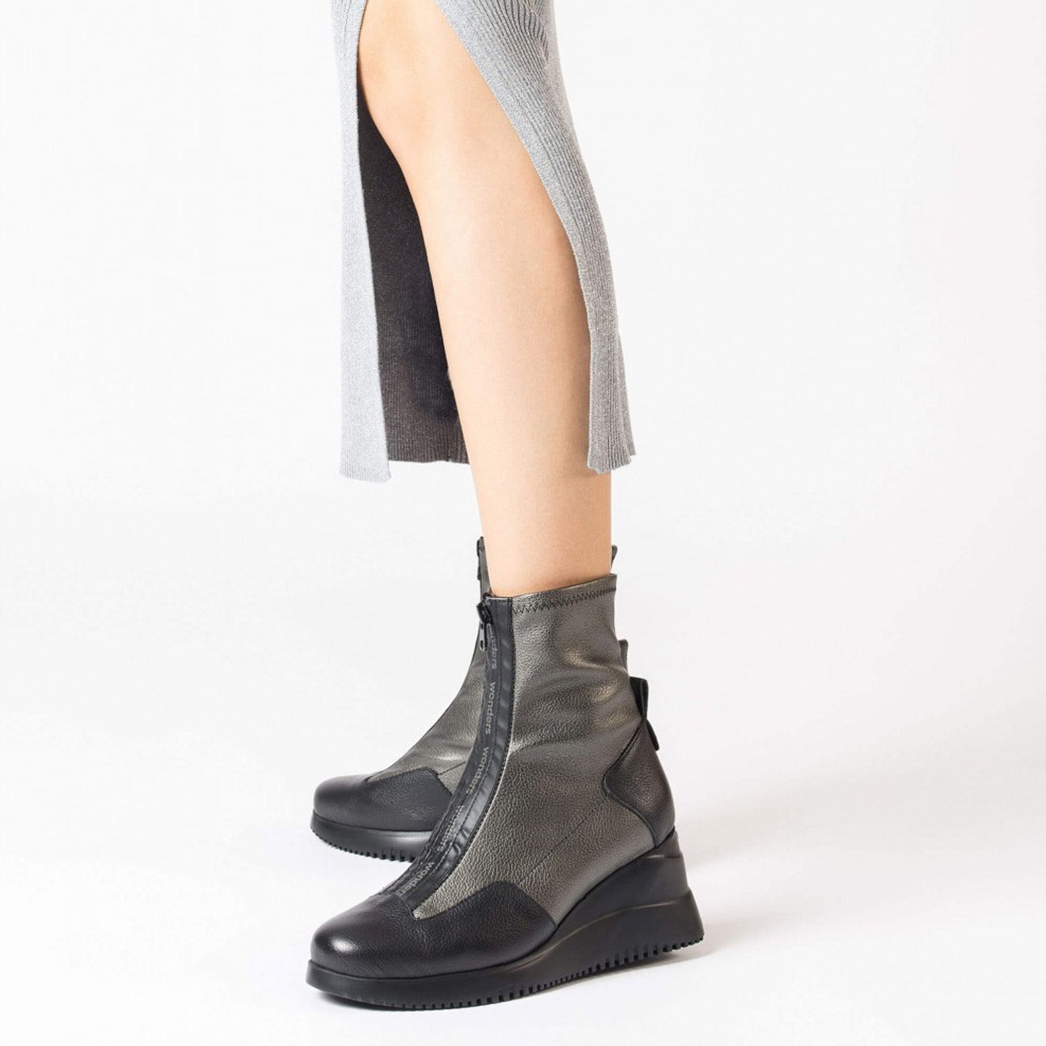 Metaliczne botki Wonders w stylizacji – modelka nosi je z czarną spódnicą.