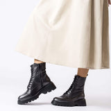 Czarne botki Wonders w stylizacji z jasną sukienką, widok na nodze modelki.