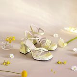 Limonkowe sandały Wonders na obcasie w artystycznej aranżacji z kwiatami.