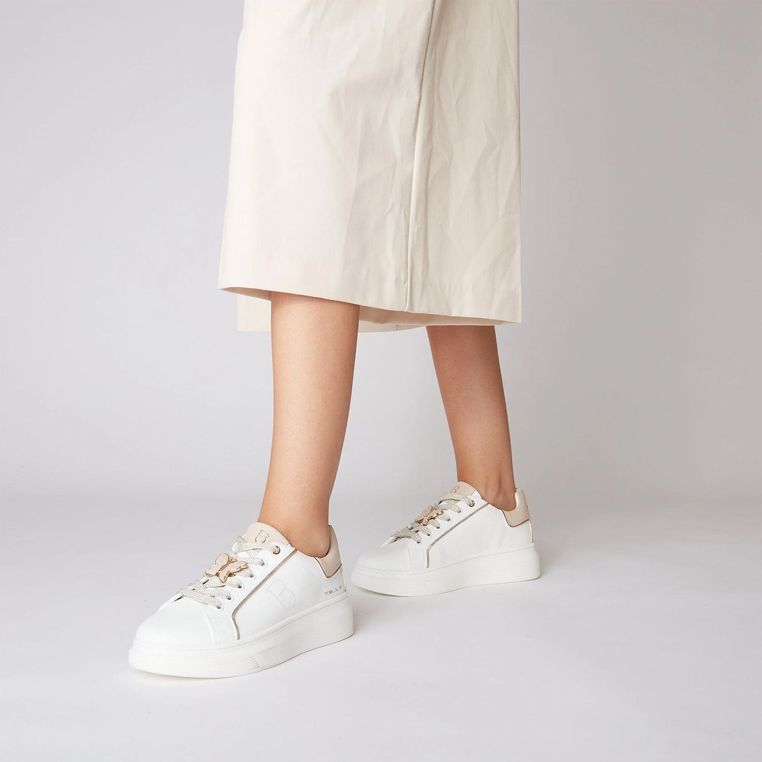 Białe sneakersy Tosca Blu w stylizacji, noszone z białą sukienką.