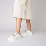 Białe sneakersy Tosca Blu w stylizacji, noszone z białą sukienką.