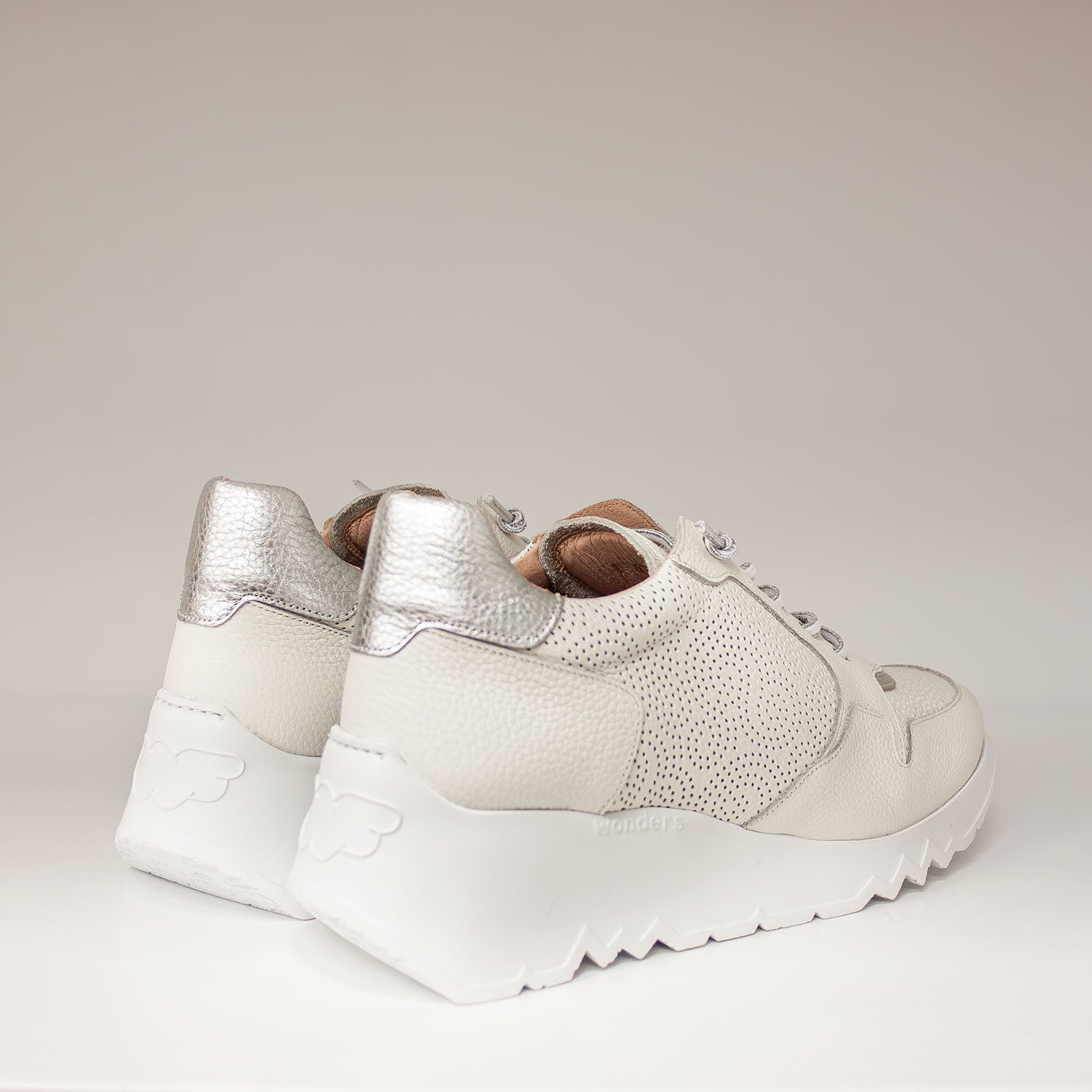 Sneakersy Wonders w kolorze białym z metalicznym zapiętkiem, prezentowane od tyłu, z widoczną lekką platformą i tłoczonym logo marki.