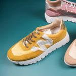 Buty sportowe Wonders w modnym, musztardowym kolorze, sfotografowane od góry w otoczeniu innych sneakersów Wonders.