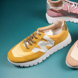 Buty sportowe Wonders w modnym, musztardowym kolorze, sfotografowane od góry w otoczeniu innych sneakersów Wonders.