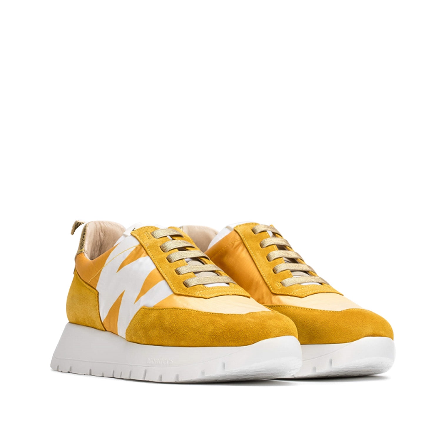 Sneakersy w ciepłym odcieniu żółci, z kontrastową białą podeszwą i ozdobnymi przeszyciami, widoczne pod lekkim kątem.