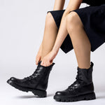 Czarne botki Wonders CAMILA w stylizacji – modelka zapina buty na suwak.