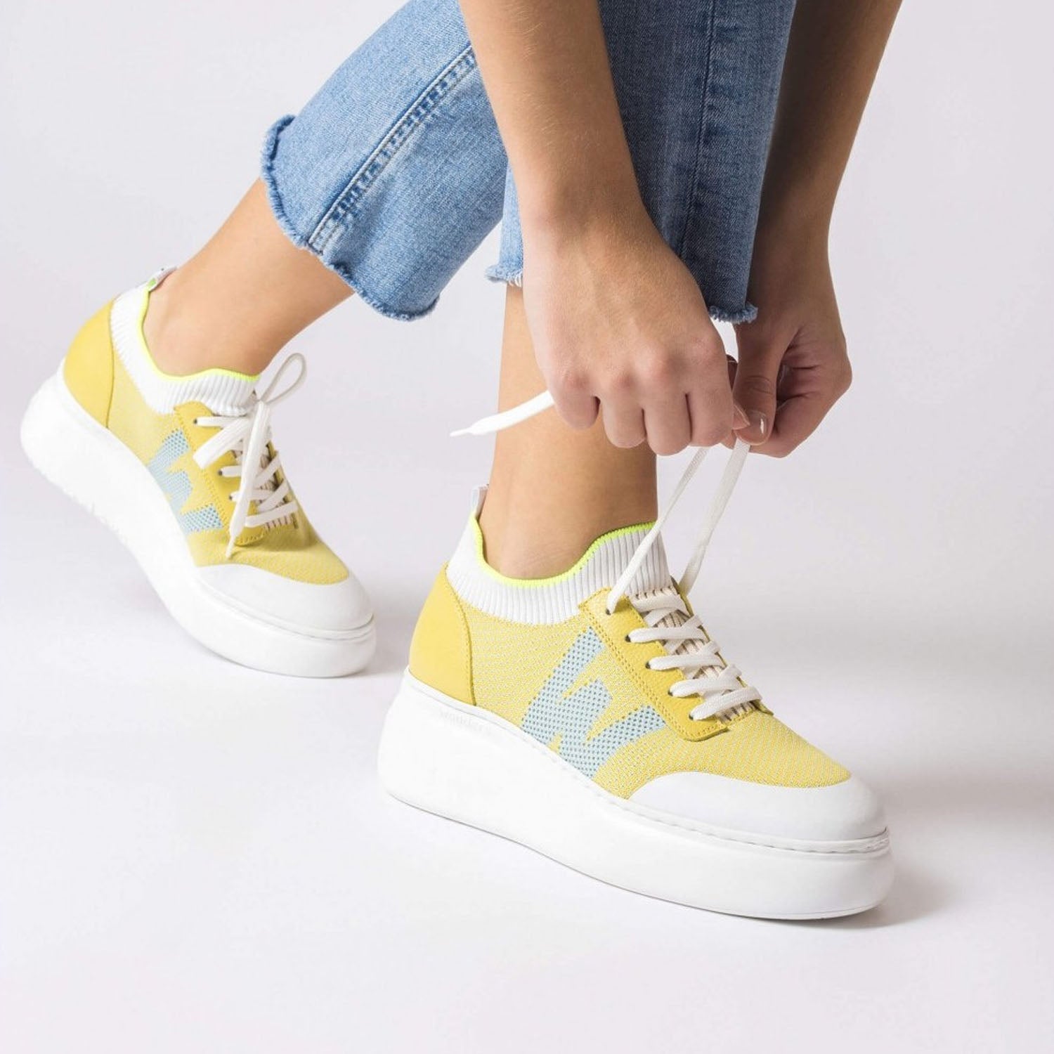 Żółte sneakersy Wonders w stylizacji, zakładane na stopy.